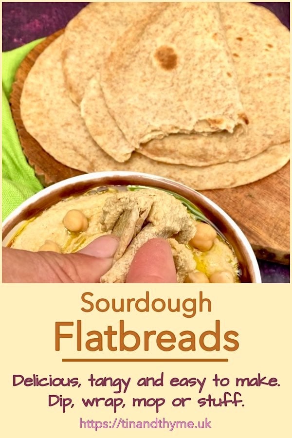 Sourdough flatbread being dipped into a bowl of hummus.