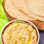 Sourdough tortilla type flatbreads with bowl of hummus at the fore.