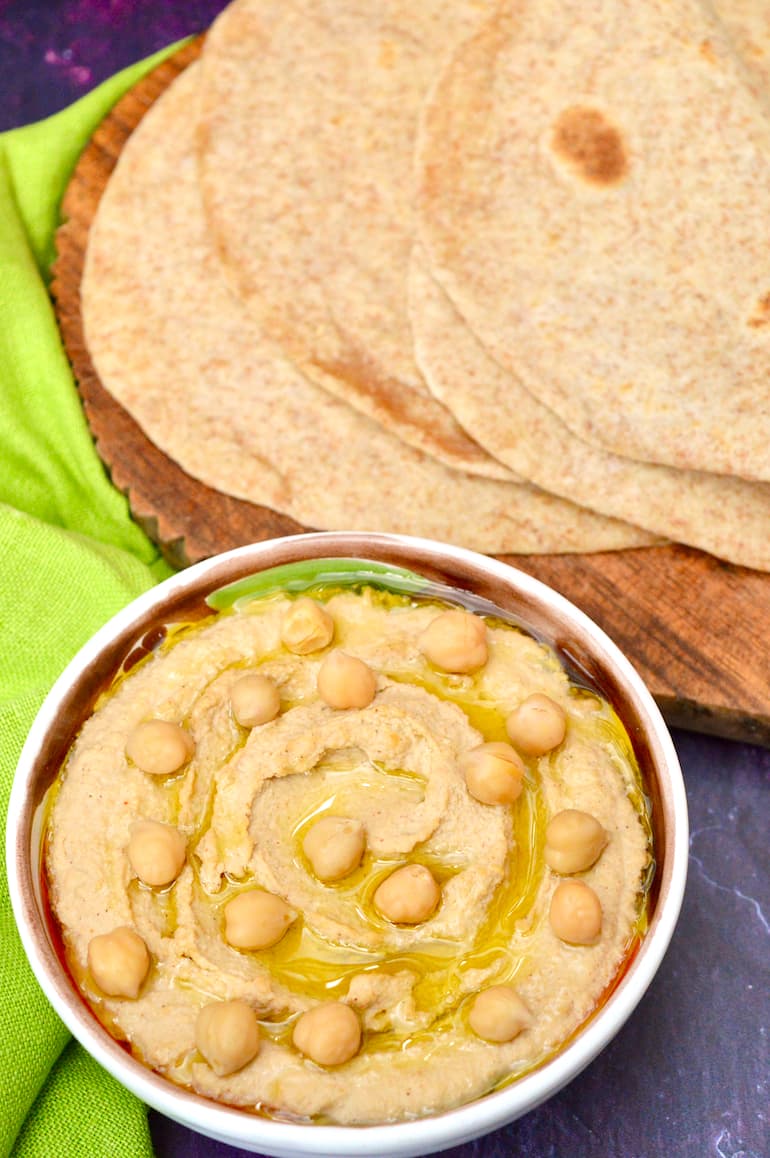 Sourdough tortilla type flatbreads with bowl of hummus at the fore.