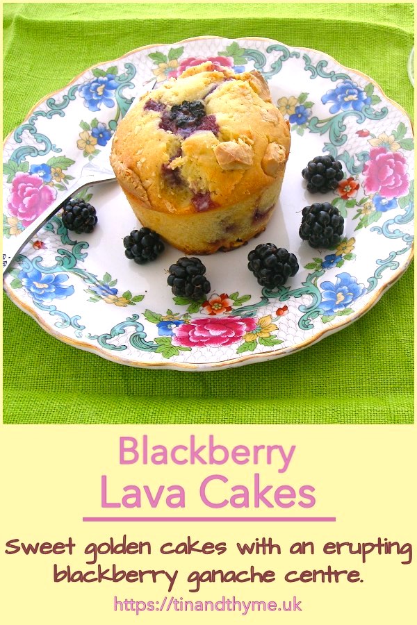 Blackberry lava cake sitting on a plate surrounded by blackberries.