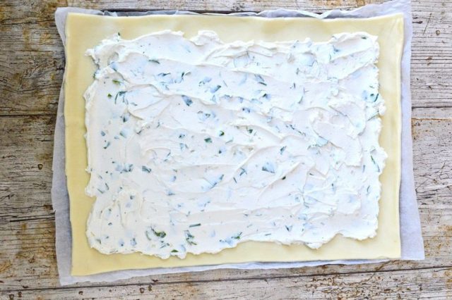 Herby cream cheese spread over raw pastry base.