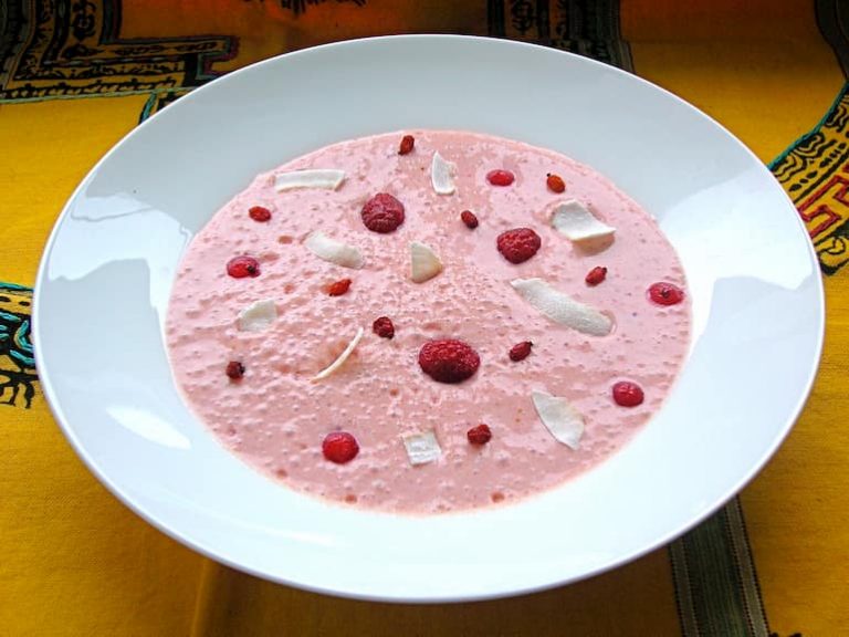 Red berry coconut smoothie bowl with raspberries and flaked coconut on top.