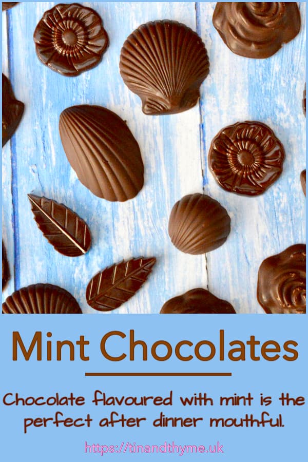 Shell shaped homemade mint chocolates laid out on a blue board.