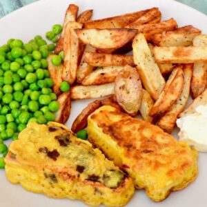 A plate of beer battered tofish (vegan fish), chips, peas and tartar sauce.