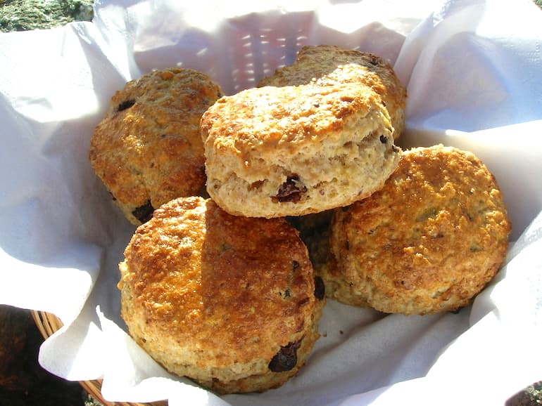 A pile of chocolate chip scones in a basket.
