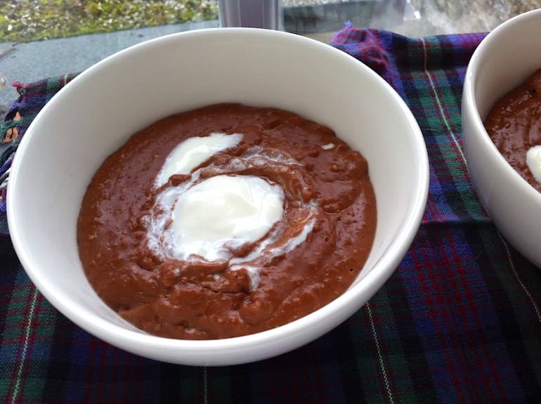 A bowl of chocolate oatmeal porridge with a swirl of yoghurt.