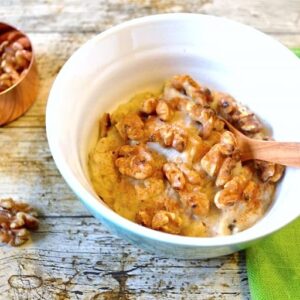 Bowl of prune porridge topped with toasted walnuts and cinnamon.