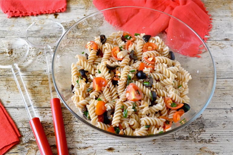 A glass bowl of Sicilian Pasta Salad with Tomatoes, Olives & Fresh Herbs.