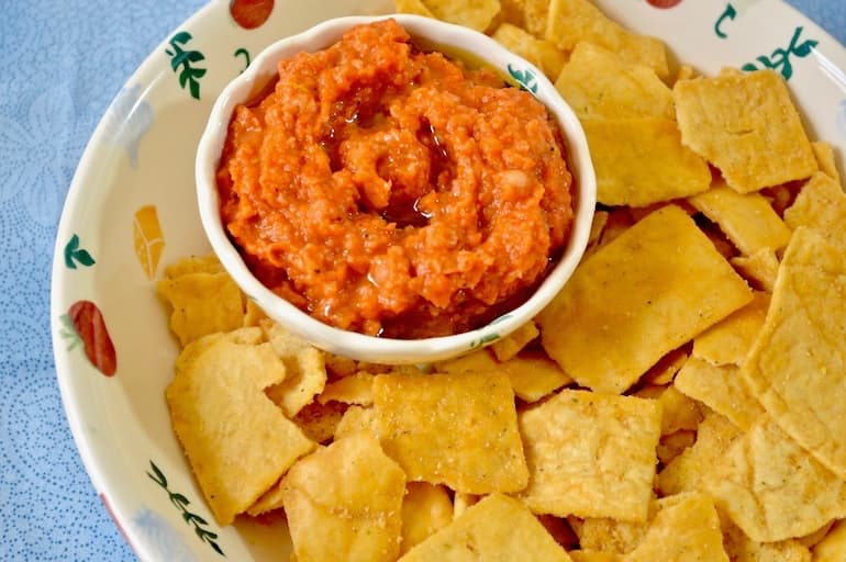 Smoky red pepper dip sitting in a bowl of chips.