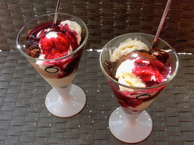 Two glasses of Chocolate and Blackcurrant Sundae Royale with chocolate sauce and blackcurrant sauce.