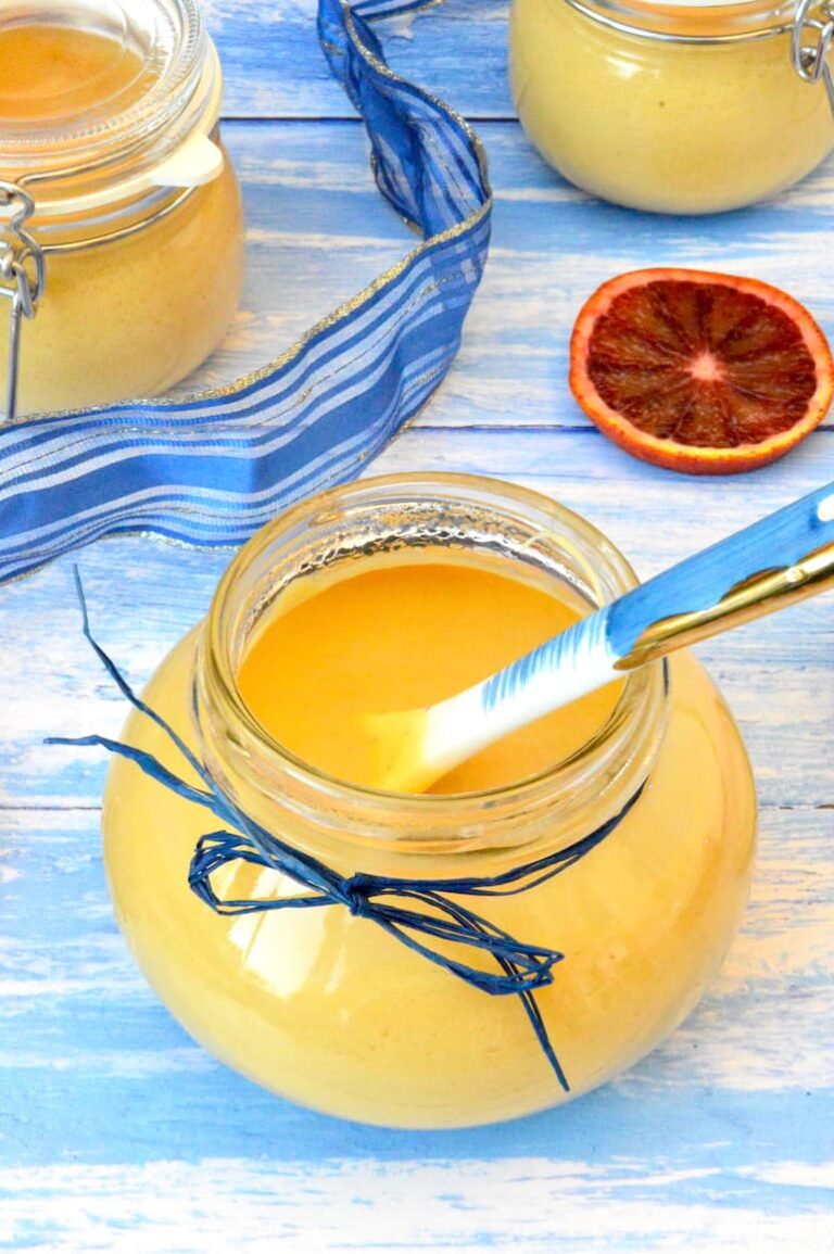 Open jar of blood orange curd with spoon inside.