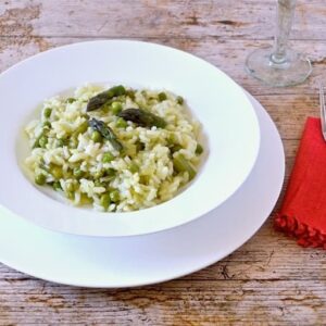A bowl of Cornish Asparagus Risotto with red napkin and fork.