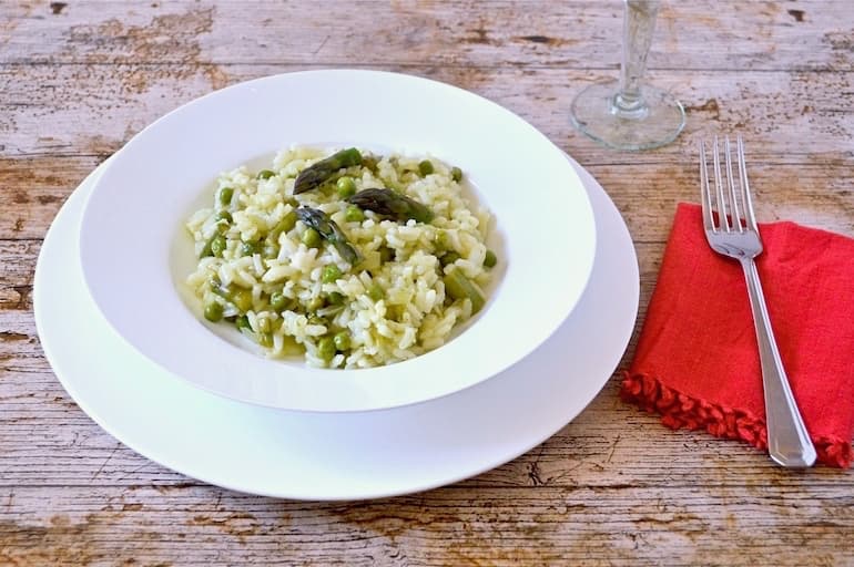 A bowl of Cornish Asparagus Risotto with red napkin and fork.