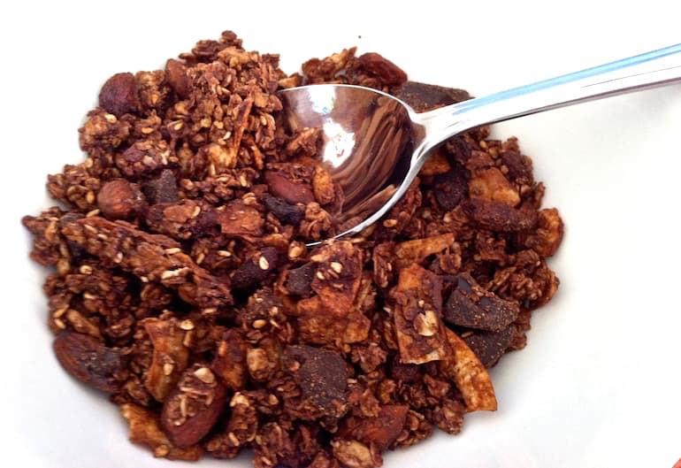 A bowl of homemade chocolate granola with spoon.