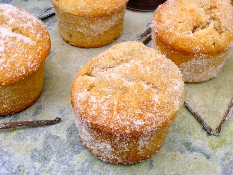 Jam doughnut muffins on slate with vanilla pods scattered about.