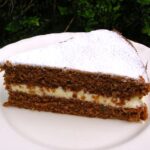 A slice of marmalade cream cake on a white plate.