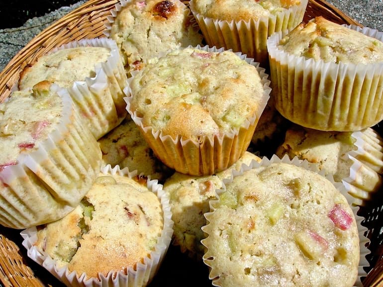 A pile of rhubarb and white chocolate muffins in a basket.