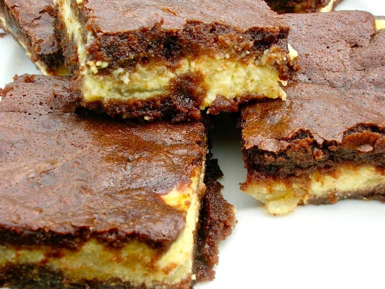 A plate of apple cheesecake brownies stacked on top of each other.
