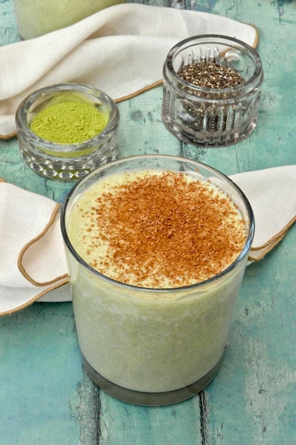 A glass of banana matcha smoothie with grated chocolate on the top.