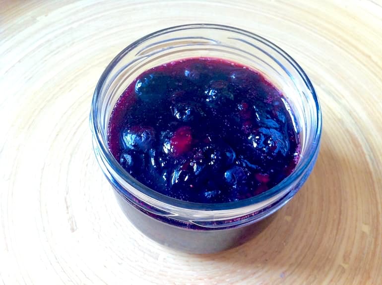 A small jar of blueberry & rose jam with no lid.