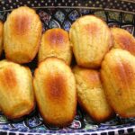 A plate of yellow honey madeleine sponges on a patterned plate.