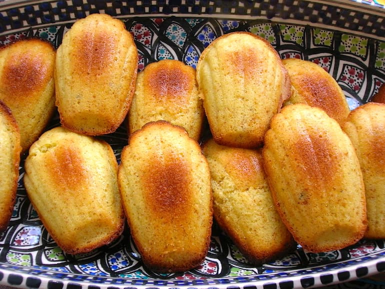 A plate of yellow honey madeleine sponges on a patterned plate.