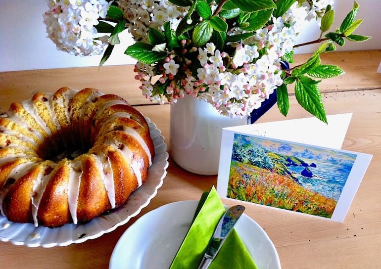 Rhubarb and ginger cake alongside a card and jug of flowers.