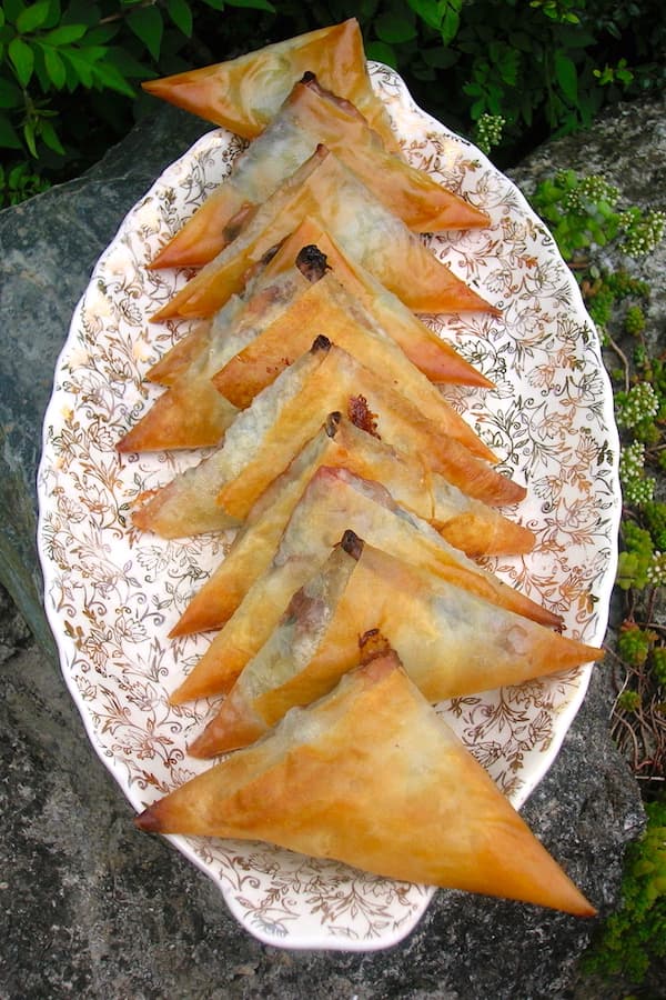 A plate of spinach filo pastries with chocolate and goat's cheese.