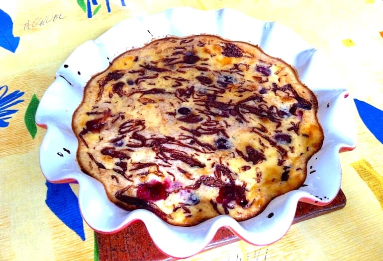 A baked Black Forest Clafoutis in a fluted dish swirled with chocolate.