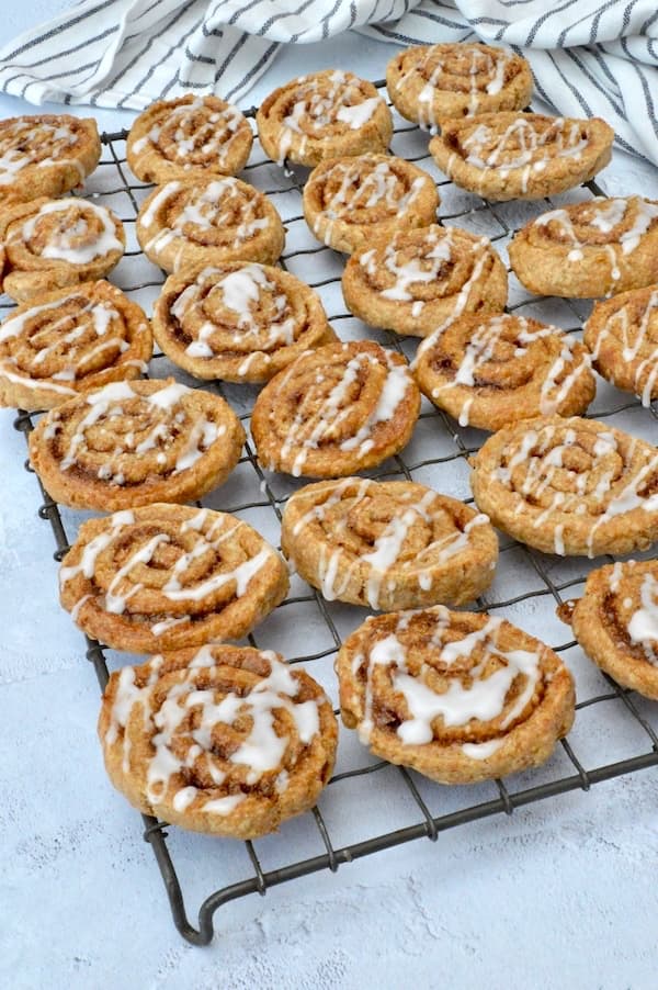 Iced cinnamon swirls cooling on a wire rack.