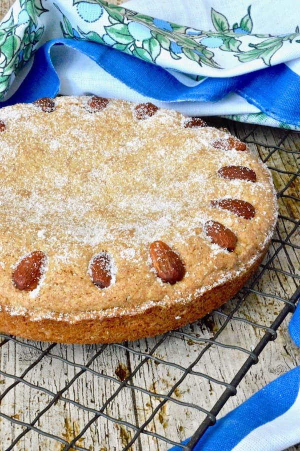 A simple almond cake cooling on a wire rack.