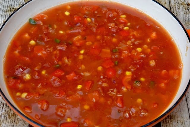 Tomato rice in a large pan, just starting to cook.