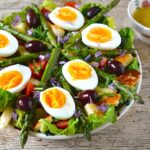 A bowl of vegetarian halloumi and asparagus salade Niçoise with dressing to the side.