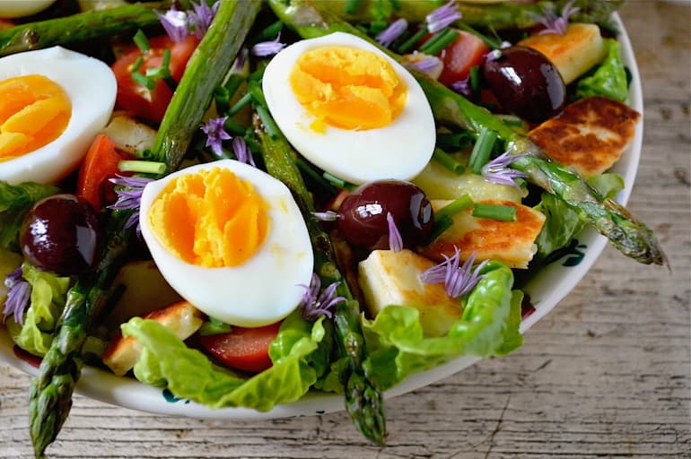 Close up of a bowl of halloumi and asparagus vegetarian Niçoise salad.