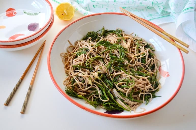 A large bowl of samphire and noodles with chopsticks.