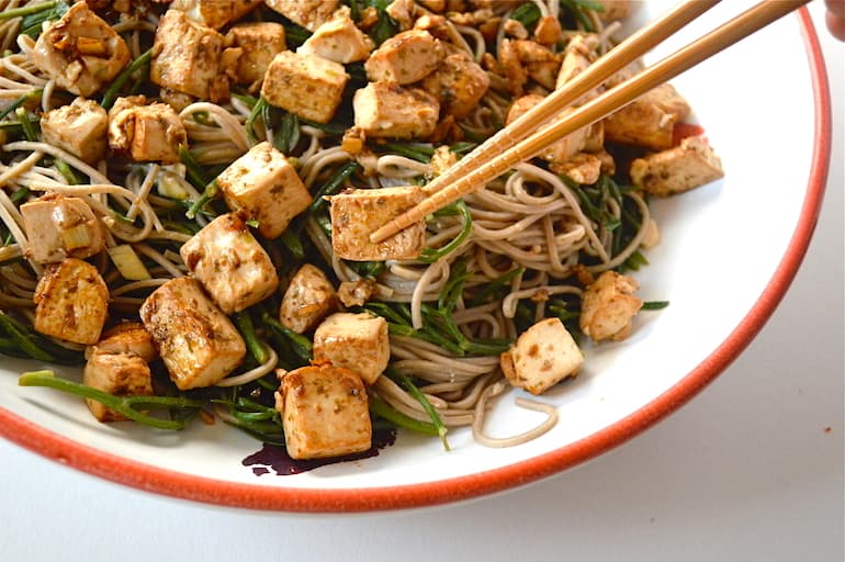 A partial bowl of samphire noodles with miso marinated tofu and chopsticks.