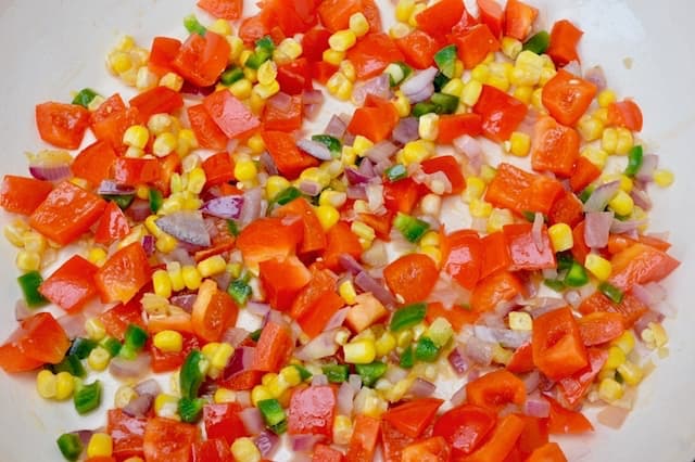 Diced colourful vegetables frying in a pan.