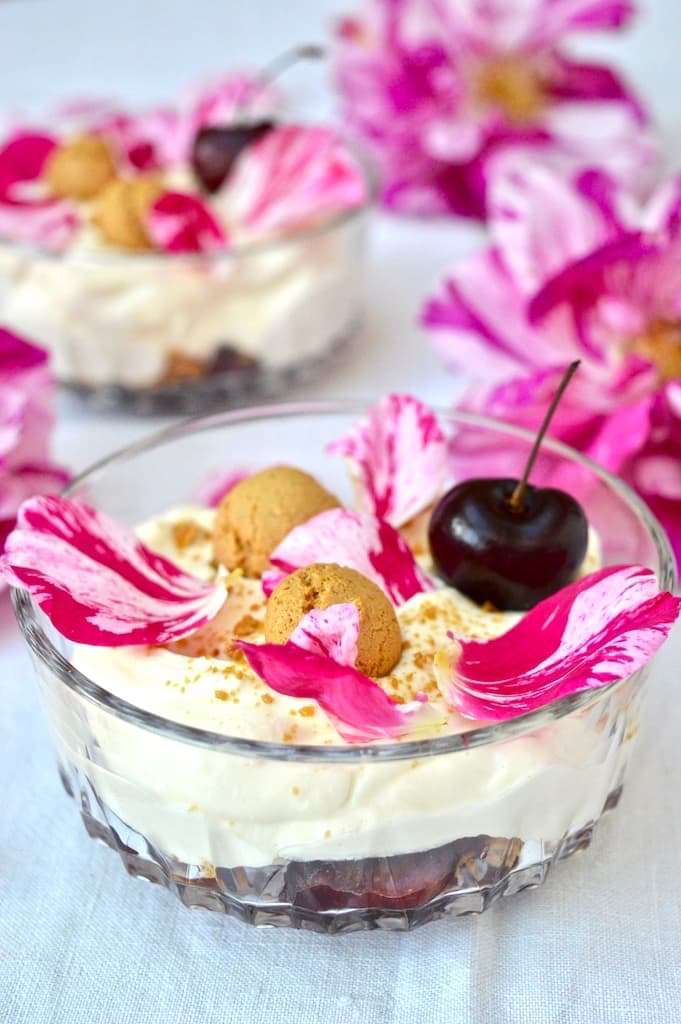 A glass bowl of very cherry cream dessert with amaretti and rosa mundi petals.