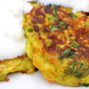 Two spiced courgette fritters with yoghurt spooned over the top.