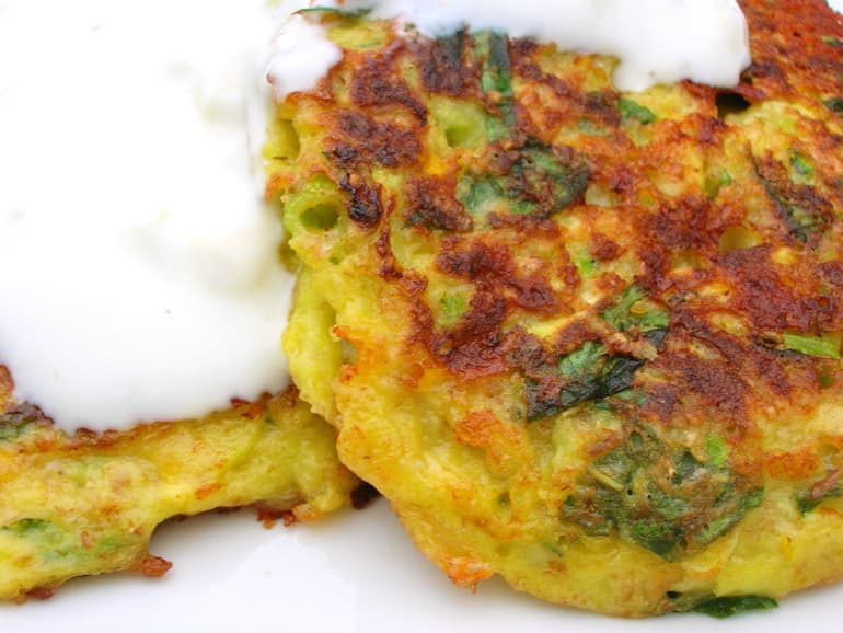 Two spiced courgette fritters with yoghurt spooned over the top.