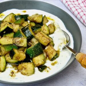 Courgettes with yoghurt and za'atar in a grey bowl.