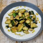Za'atar spiced courgettes with yoghurt in a grey bowl.