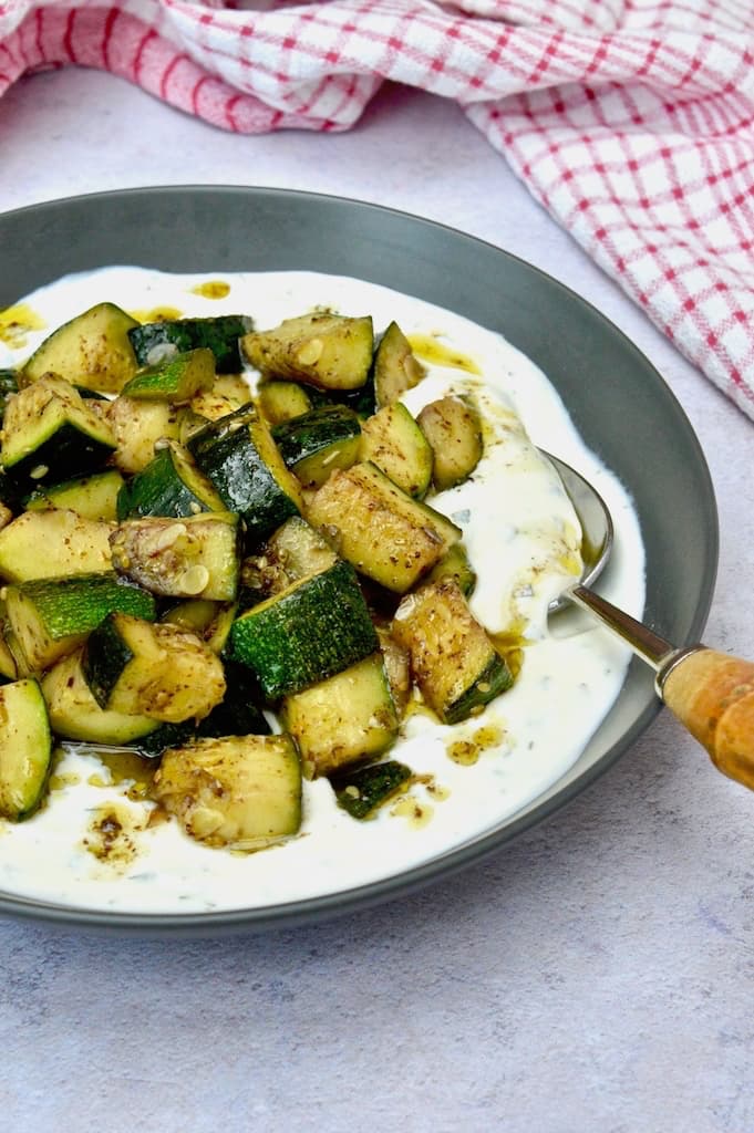 Courgettes with yoghurt and za'atar in a grey bowl.