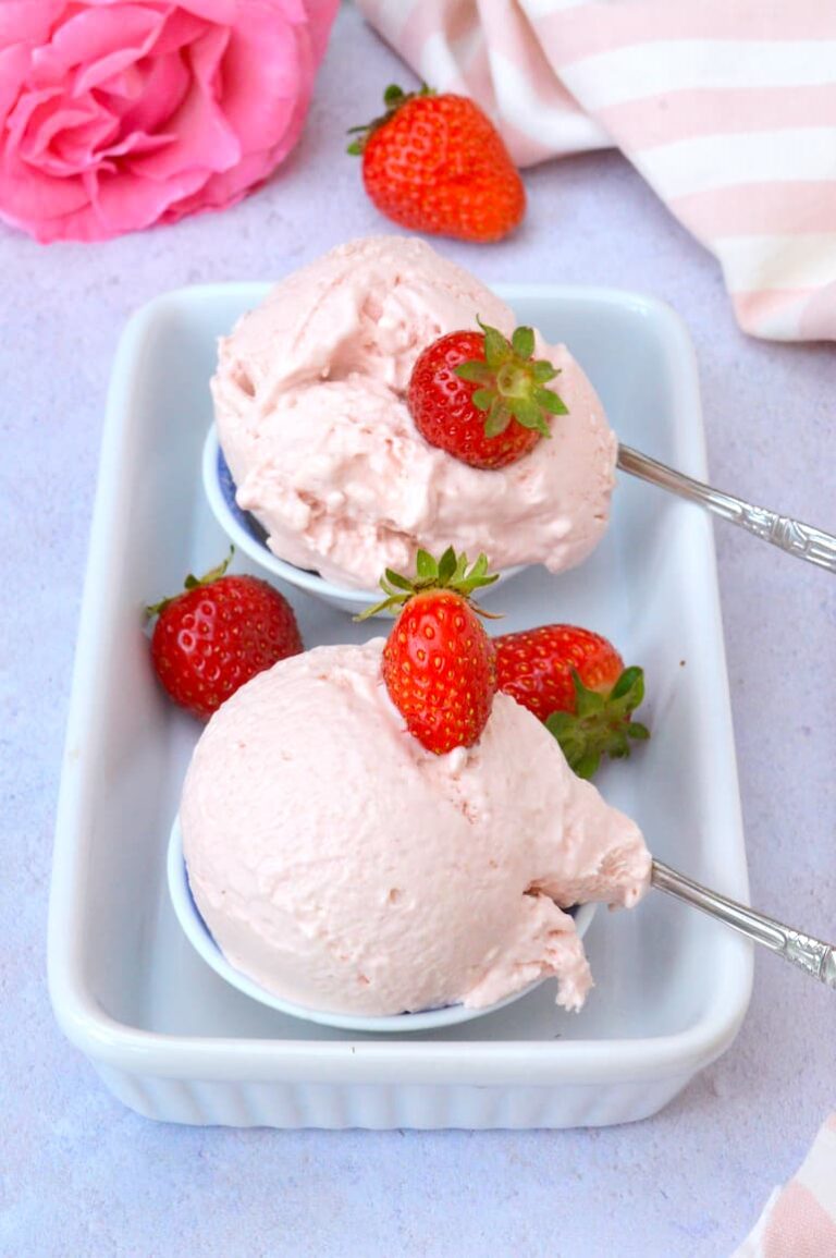 Two scoops of easy no-churn strawberry ice cream on white ceramic tray.