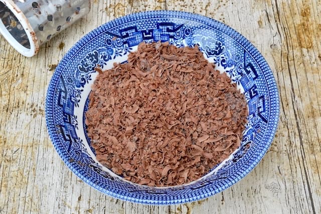 A blue bowl of grated dark chocolate. One of the key ingredients for healthier baking.