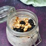 Clip top jar with blackberry overnight oats, toasted hazelnuts and honey drizzled on top.