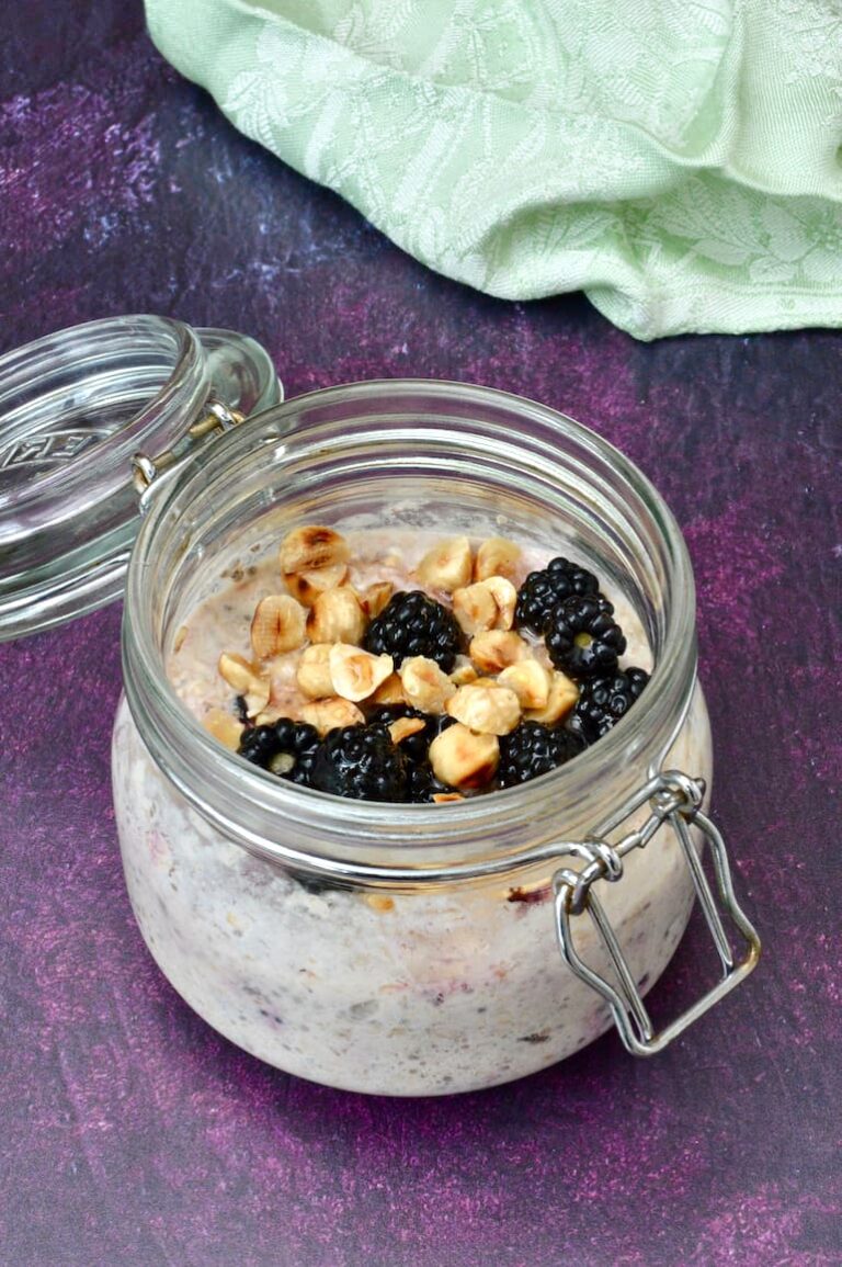 Clip top jar with blackberry overnight oats, toasted hazelnuts and honey drizzled on top.