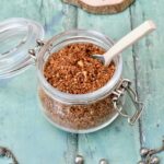 Open jar of Egyptian dukkah spice mix with spoon sticking out.