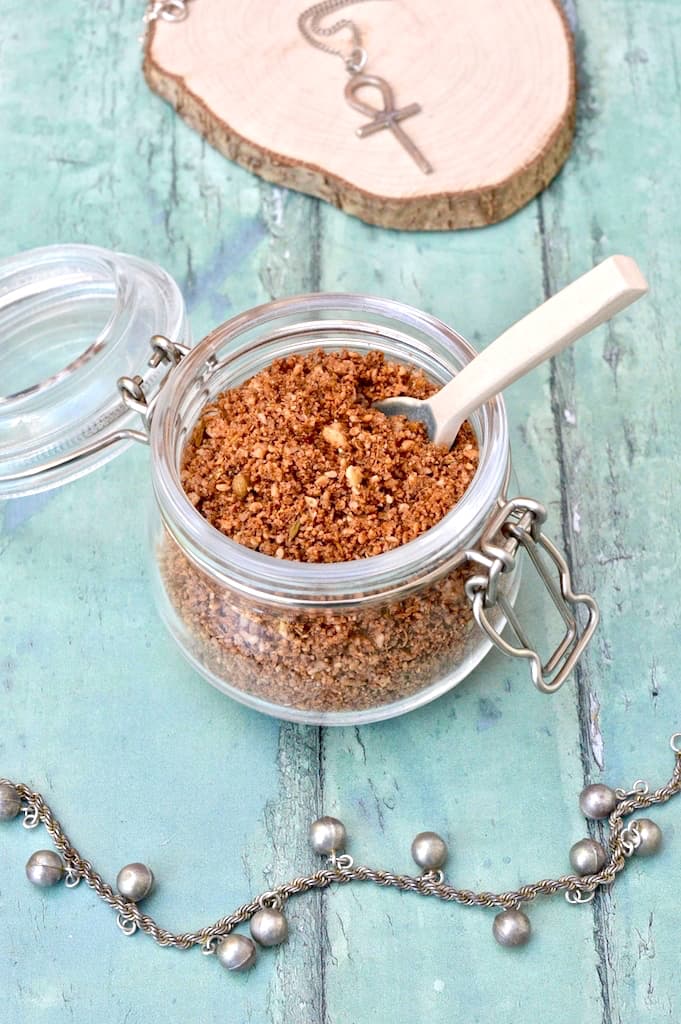 An open jar of Egyptian dukkah spice mix with a spoon sticking out.
