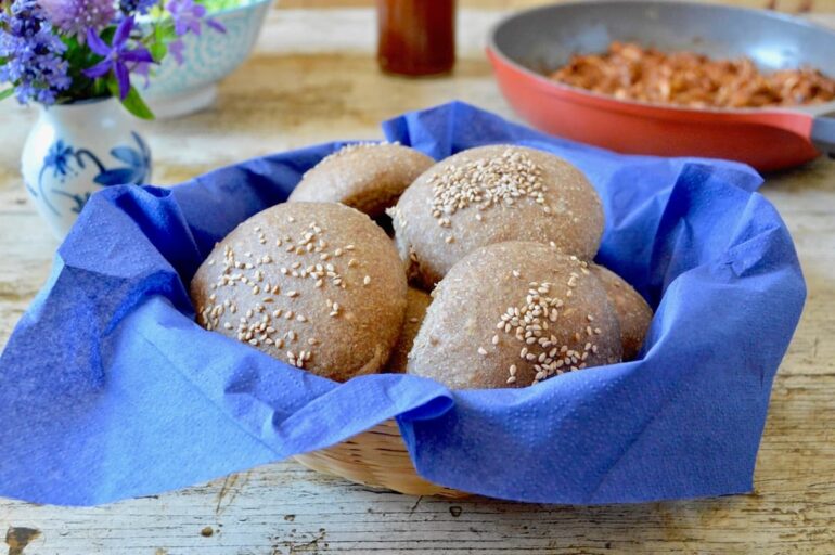 Wholemeal spelt burger buns in a blue lined basket.